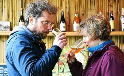 Deux personnes face à face sentent le cidre présen dans leurs verres à dégustation, dans un local de vente de produits locaux